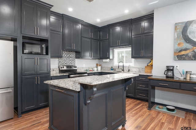 kitchen featuring appliances with stainless steel finishes, dark hardwood / wood-style floors, light stone countertops, sink, and a center island