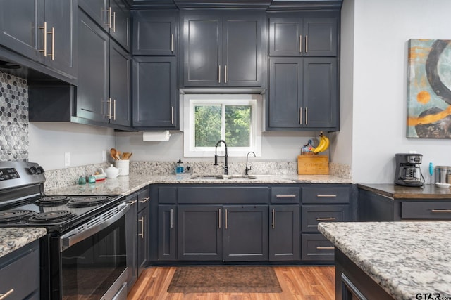 kitchen with light wood-type flooring, sink, light stone counters, and stainless steel electric stove