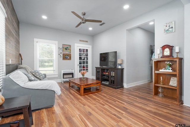 living room featuring hardwood / wood-style floors, ceiling fan, and heating unit