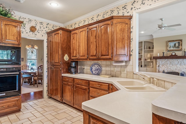 kitchen featuring sink, black appliances, crown molding, and decorative light fixtures