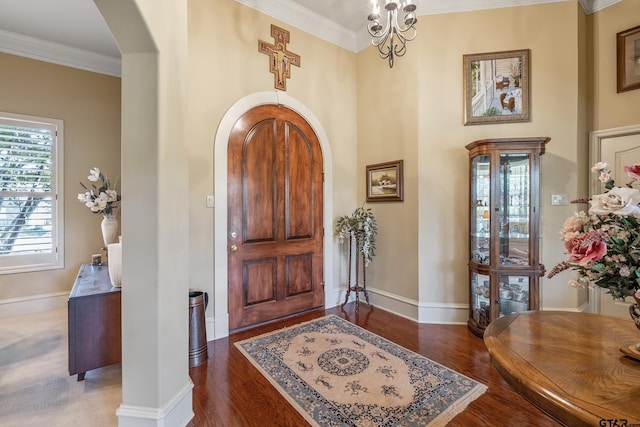 entryway featuring ornamental molding, dark wood-type flooring, and a notable chandelier