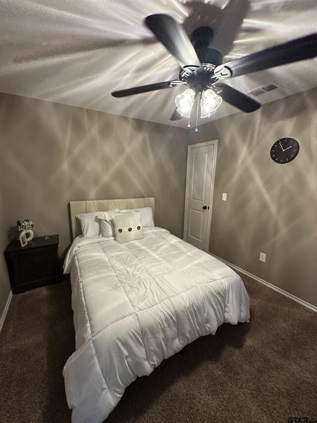 bedroom featuring a textured ceiling, visible vents, baseboards, carpet, and a ceiling fan