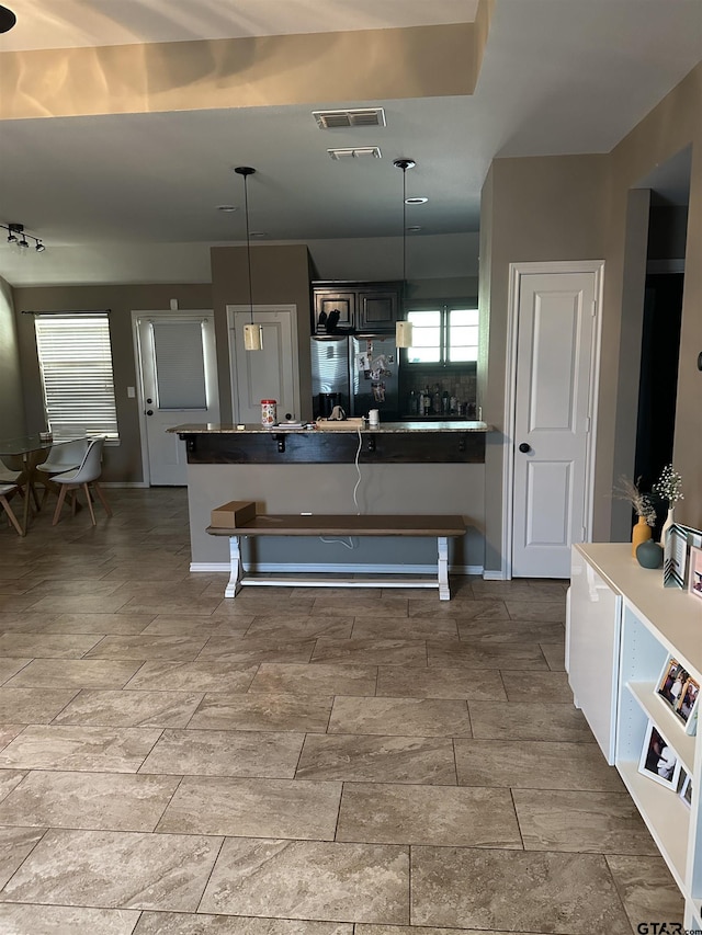 kitchen with pendant lighting, dark countertops, visible vents, freestanding refrigerator, and stainless steel fridge with ice dispenser