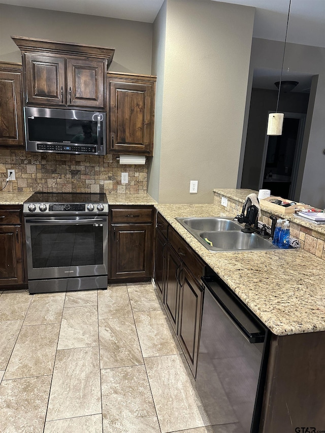 kitchen featuring backsplash, a peninsula, appliances with stainless steel finishes, and a sink