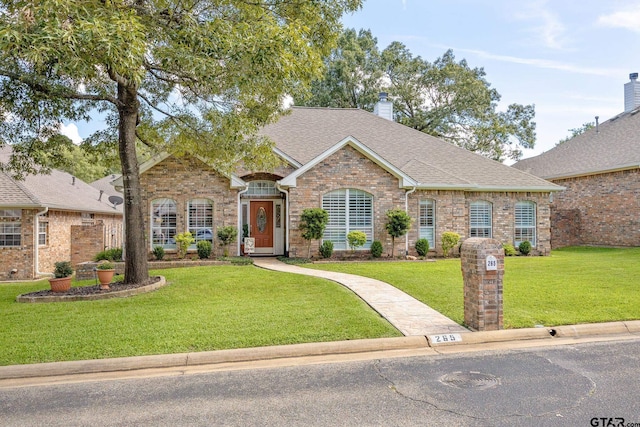 265 Bunker Dr, Tyler, TX 75703 - view of front of property with a front yard, a shingled roof, brick siding, and a chimney