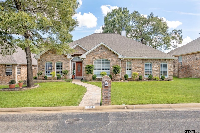 265 Bunker Dr, Tyler, TX 75703 - view of front of house with a front lawn, a chimney, a shingled roof, and brick siding