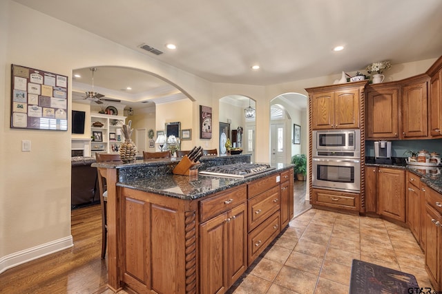 265 Bunker Dr, Tyler, TX 75703 - kitchen featuring appliances with stainless steel finishes, open floor plan, a breakfast bar, ornamental molding, and dark stone countertops