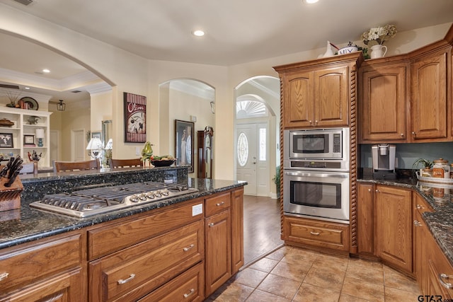 265 Bunker Dr, Tyler, TX 75703 - kitchen with stainless steel appliances, arched walkways, dark stone countertops, brown cabinets, and recessed lighting