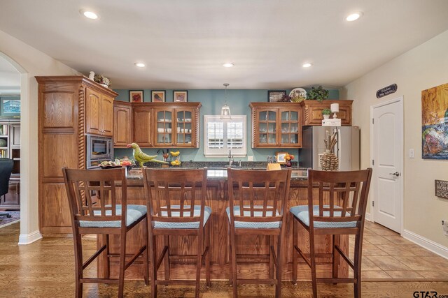 265 Bunker Dr, Tyler, TX 75703 - kitchen with stainless steel appliances, glass insert cabinets, recessed lighting, arched walkways, and a kitchen bar