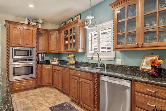 265 Bunker Dr, Tyler, TX 75703 - kitchen featuring stainless steel appliances, brown cabinets, decorative light fixtures, dark stone counters, and glass insert cabinets