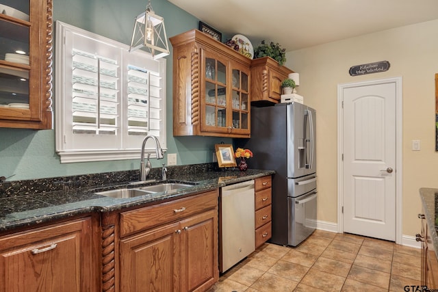 265 Bunker Dr, Tyler, TX 75703 - kitchen featuring appliances with stainless steel finishes, brown cabinetry, glass insert cabinets, dark stone counters, and light tile patterned floors