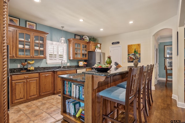265 Bunker Dr, Tyler, TX 75703 - kitchen featuring appliances with stainless steel finishes, arched walkways, a center island, brown cabinetry, and a breakfast bar