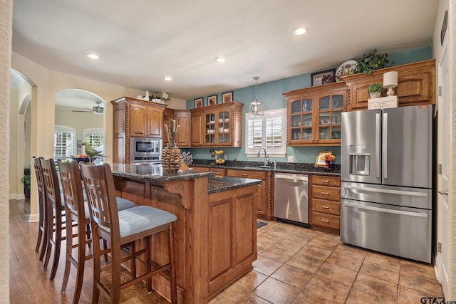 265 Bunker Dr, Tyler, TX 75703 - kitchen with appliances with stainless steel finishes, brown cabinets, healthy amount of natural light, glass insert cabinets, and recessed lighting