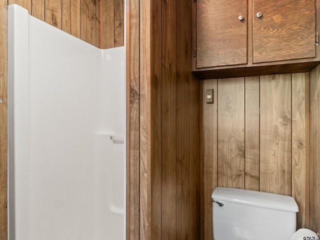 bathroom featuring wooden walls and toilet