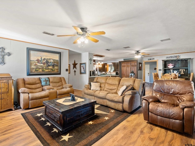 living room featuring light hardwood / wood-style flooring, ornamental molding, and ceiling fan