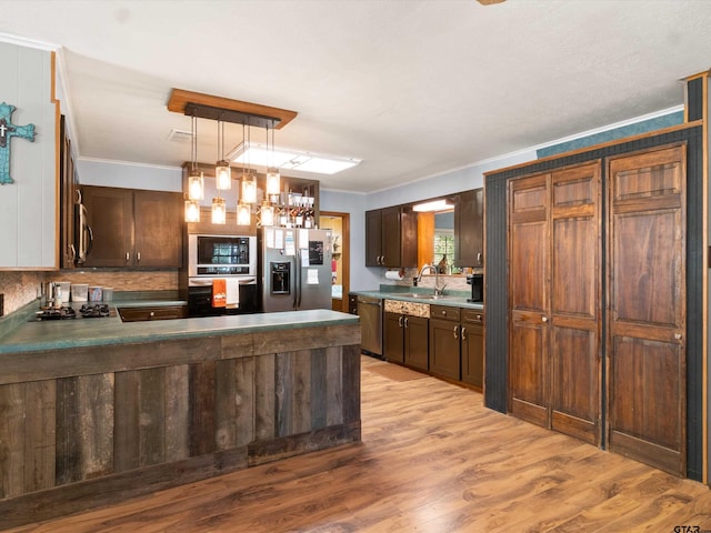 kitchen with sink, light wood-type flooring, ornamental molding, pendant lighting, and stainless steel appliances