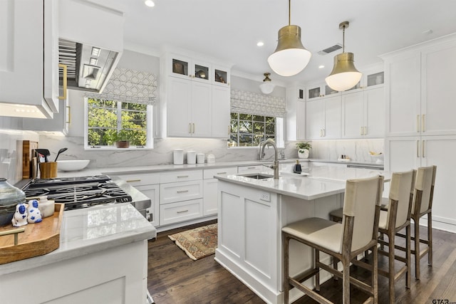 kitchen with a center island with sink, decorative light fixtures, dark hardwood / wood-style flooring, and white cabinets