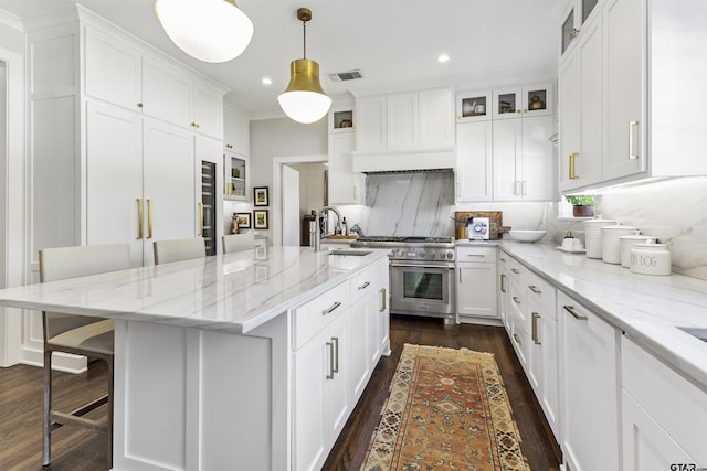 kitchen with decorative backsplash, a breakfast bar, sink, decorative light fixtures, and an island with sink