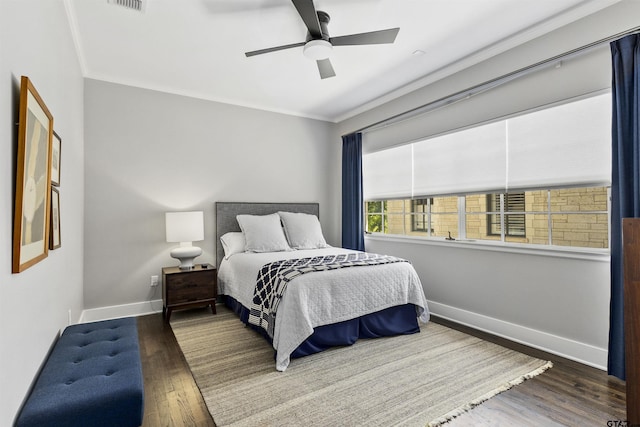 bedroom featuring dark hardwood / wood-style flooring, ceiling fan, and ornamental molding