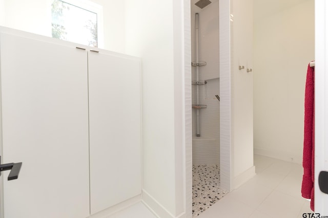 bathroom featuring tiled shower and tile patterned flooring