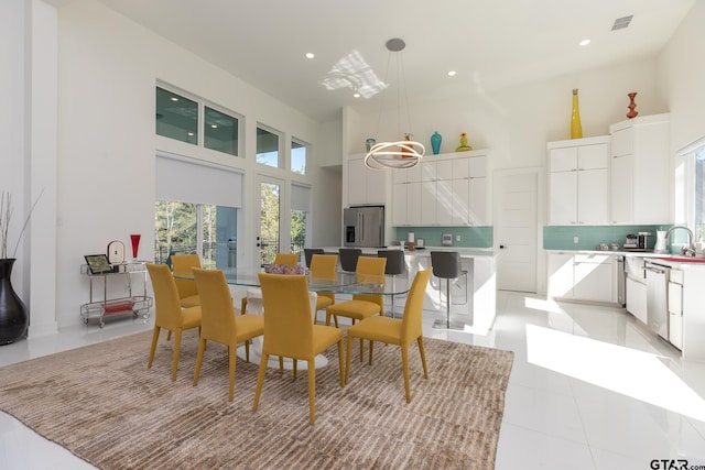 tiled dining room featuring a high ceiling and sink