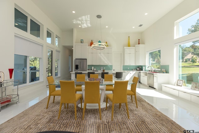 dining area featuring light tile patterned floors, sink, and a high ceiling