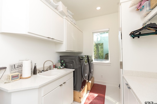 laundry room with cabinets, washer and clothes dryer, and sink