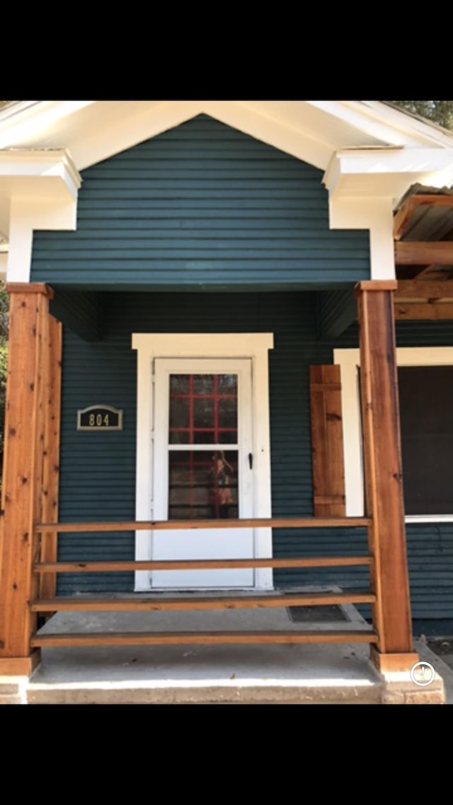 view of exterior entry featuring covered porch