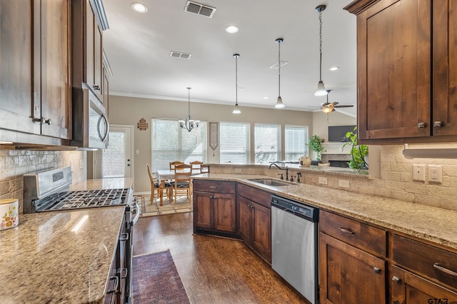 kitchen featuring light stone counters, ceiling fan with notable chandelier, stainless steel appliances, sink, and decorative light fixtures