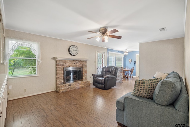 living room with hardwood / wood-style floors, a brick fireplace, and plenty of natural light