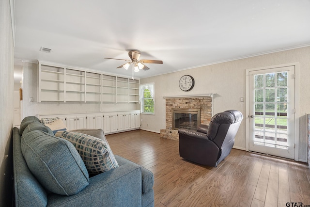 living room with ceiling fan, hardwood / wood-style flooring, a brick fireplace, and plenty of natural light