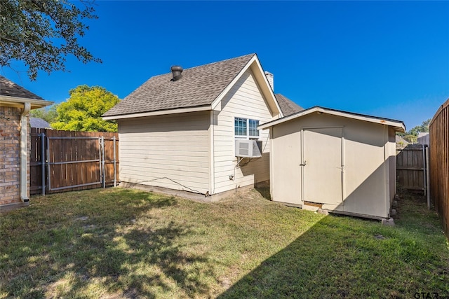 rear view of property featuring a lawn, cooling unit, and a storage unit