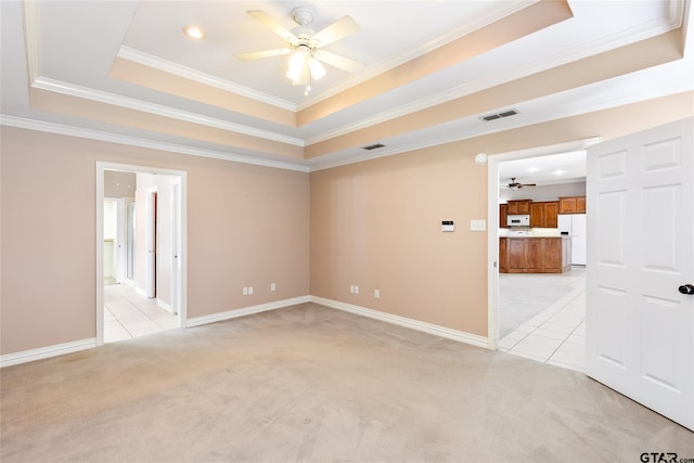 carpeted spare room with ceiling fan, ornamental molding, and a tray ceiling