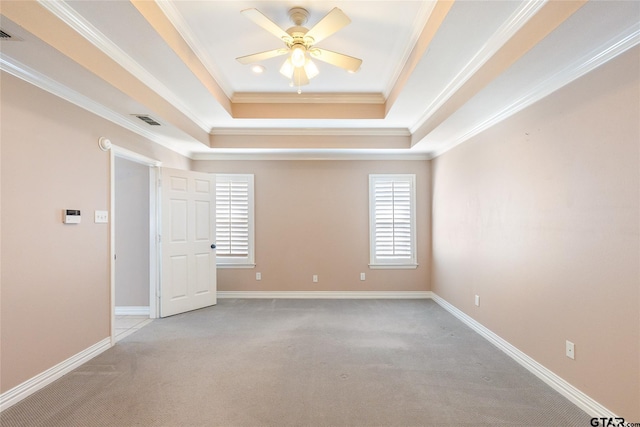 carpeted empty room with a raised ceiling, ceiling fan, and ornamental molding