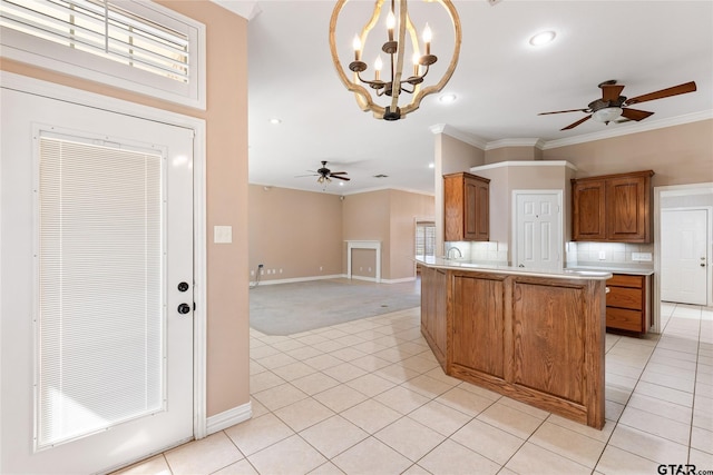 kitchen with ornamental molding, ceiling fan with notable chandelier, kitchen peninsula, and hanging light fixtures