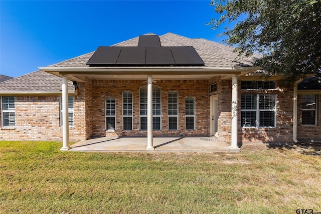 rear view of house featuring a lawn, solar panels, and a patio