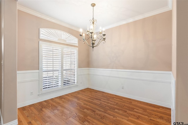 spare room with hardwood / wood-style floors, ornamental molding, and a notable chandelier