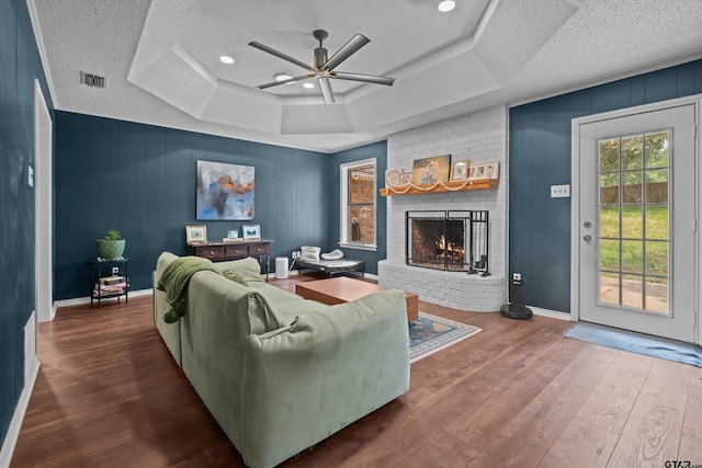 9331 Londonderry Dr, Tyler, TX 75703 - living area featuring a ceiling fan, a fireplace, a raised ceiling, wood finished floors, and a textured ceiling