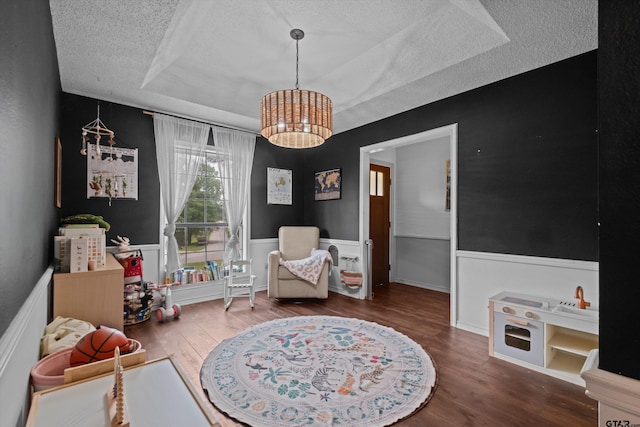 9331 Londonderry Dr, Tyler, TX 75703 - sitting room featuring a textured ceiling, a raised ceiling, a chandelier, wood finished floors, and wainscoting