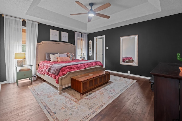 9331 Londonderry Dr, Tyler, TX 75703 - bedroom with a tray ceiling, baseboards, hardwood / wood-style flooring, a ceiling fan, and a textured ceiling