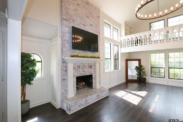 18751 Ridgeline, Tyler, TX 75703 - unfurnished living room featuring a high ceiling, a brick fireplace, healthy amount of natural light, wood finished floors, and a chandelier