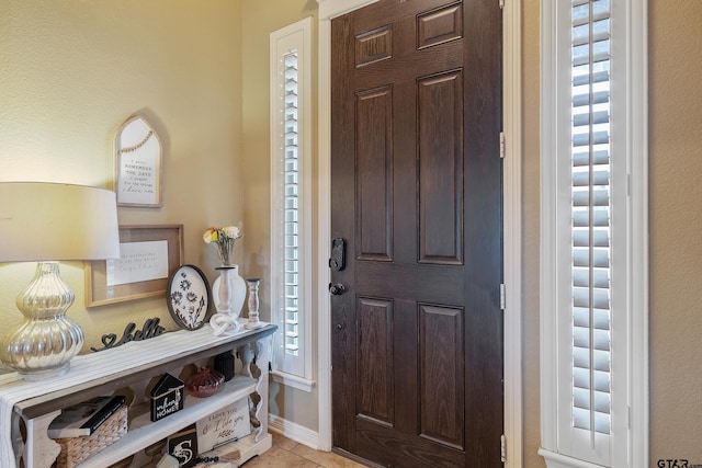 foyer entrance featuring light tile patterned floors and baseboards