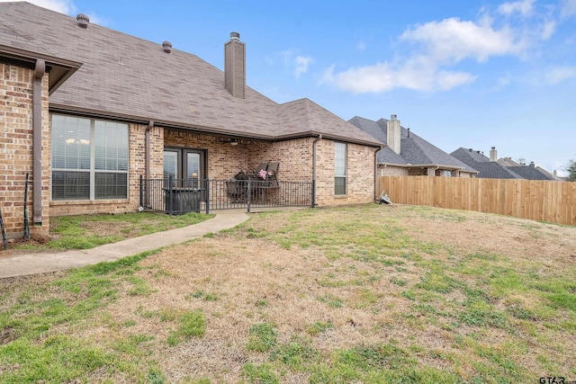 back of house with brick siding and fence