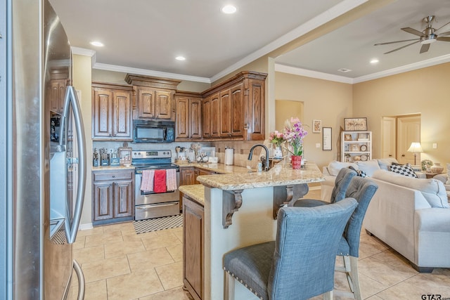 kitchen with a breakfast bar area, stainless steel appliances, open floor plan, light stone countertops, and a peninsula