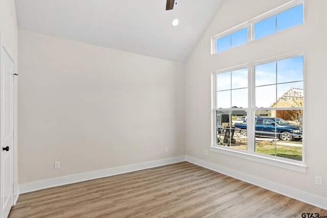 empty room with high vaulted ceiling and light hardwood / wood-style floors