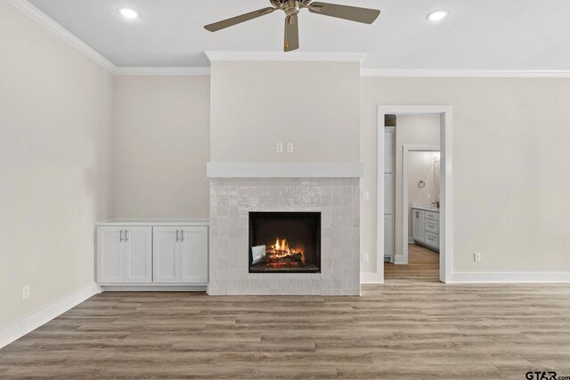 unfurnished living room featuring a fireplace, light hardwood / wood-style floors, ceiling fan, and crown molding