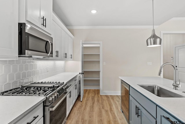 kitchen featuring stainless steel appliances, light hardwood / wood-style floors, white cabinetry, sink, and decorative light fixtures