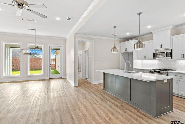 kitchen with a center island with sink, stainless steel appliances, hanging light fixtures, and sink