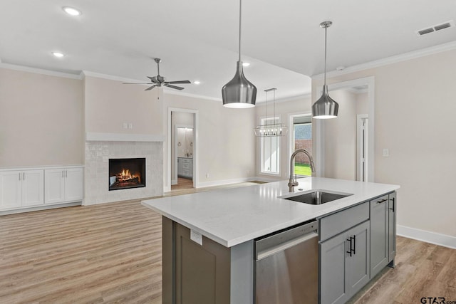 kitchen featuring sink, stainless steel dishwasher, hanging light fixtures, a kitchen island with sink, and gray cabinetry