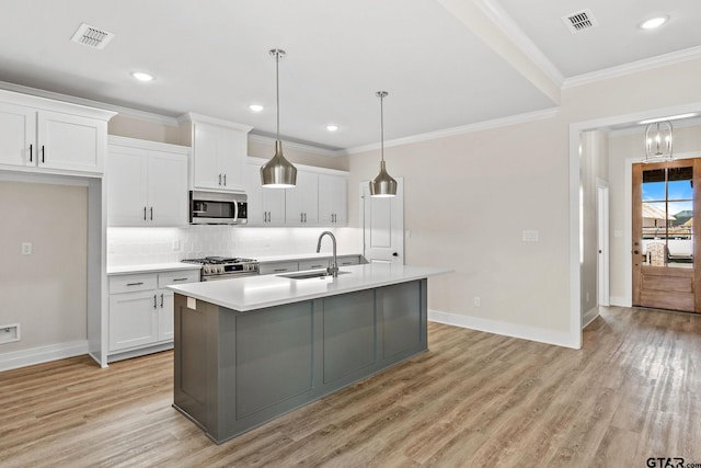 kitchen with stainless steel appliances, a center island with sink, sink, light hardwood / wood-style flooring, and white cabinets